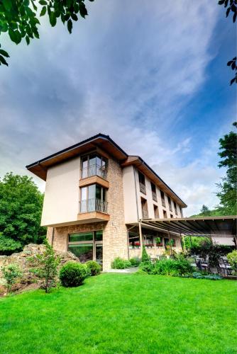 a large building with a green lawn in front of it at Hotel & Relax Zone Cattleya in Krushuna