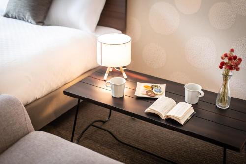 a bed room with a table with a lamp and books at BON Kyoto Station in Kyoto