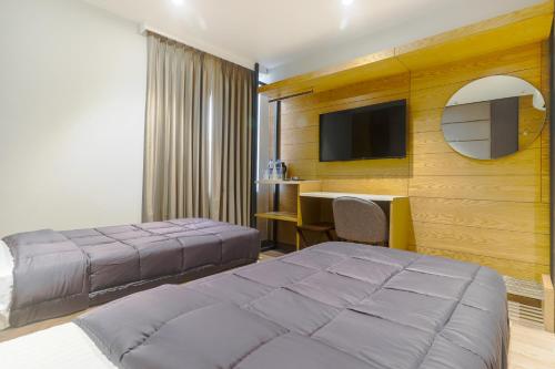 a bedroom with two beds and a desk and a tv at Hotel Bricks, Karol Bagh, New Delhi in New Delhi