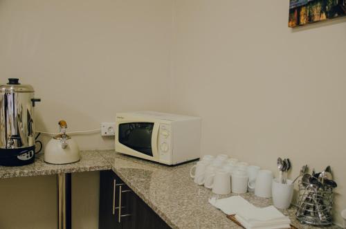 a kitchen counter with a microwave and some cups at Towers Lodge in Boksburg