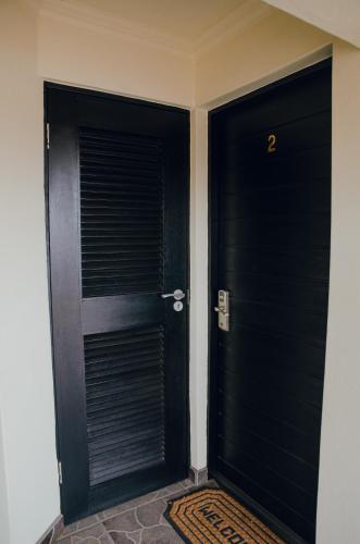 two black doors in a hallway with a rug at Towers Lodge in Boksburg