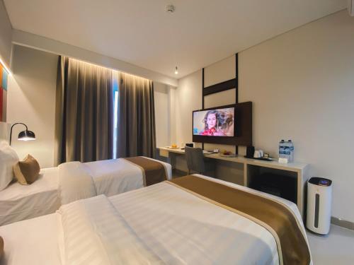 a hotel room with two beds and a flat screen tv at Patra Dumai Hotel in Dumai