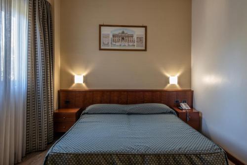 a bedroom with a bed with two lights on it at Hotel Petra in La Romanina
