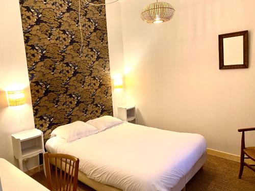 a bedroom with a white bed and a wall at La Maison de Thaïs in Arles