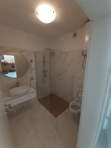 a white bathroom with a shower and a toilet at Barko apartment and rooms in Hvar