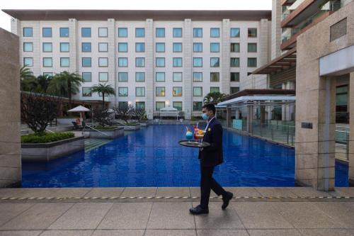 a man walking in front of a building with a tray of food at Novotel Hyderabad Airport in Hyderabad