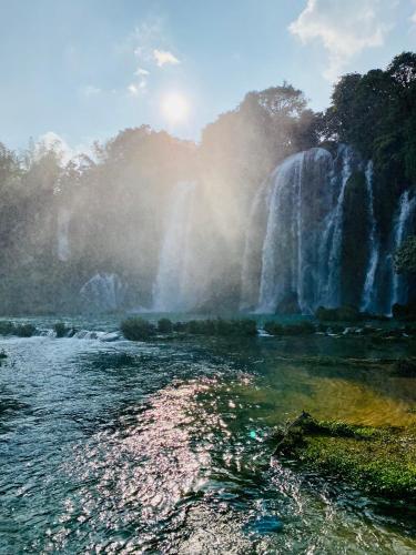 a waterfall next to a body of water with a river at Nasan Green Farm in Cao Bằng