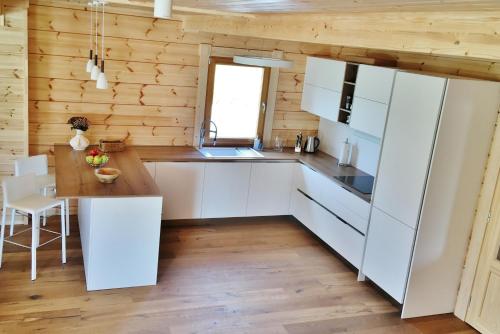 - une cuisine avec des placards blancs et un mur en bois dans l'établissement Chata Natan, à Veľká Lomnica
