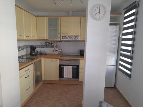 a kitchen with yellow cabinets and a clock on the wall at Apartamento Ocean in Arinaga