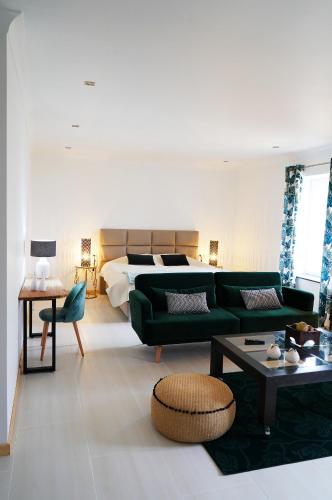 un salon avec un canapé vert et un lit dans l'établissement Château Boussas, à Couloumé-Mondébat