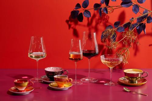 four wine glasses sitting on a table with plates at Steigenberger Icon Parkhotel Düsseldorf in Düsseldorf