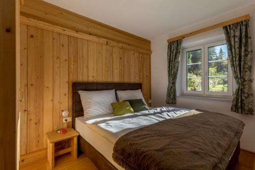 1 dormitorio con 1 cama grande y pared de madera en Appartement Hess Hinterstoder en Hinterstoder