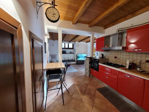 une cuisine avec des placards rouges et une horloge murale dans l'établissement Il Pozzo, à Tremezzo