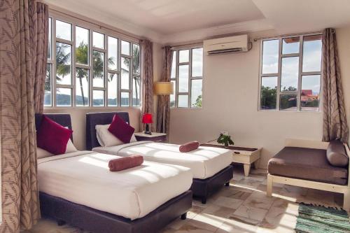 a bedroom with two beds and a desk and windows at Sandy Beach Resort By Casa Loma in Pantai Cenang