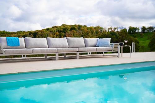 a couch sitting next to a swimming pool at Château Boussas in Couloumé-Mondébat