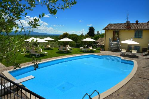 une grande piscine bleue en face d'une maison dans l'établissement Podere Del Griccia, à Civitella in Val di Chiana
