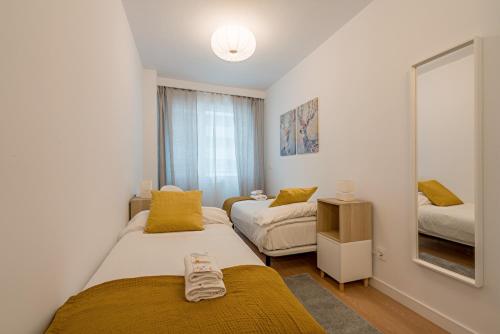 een kleine slaapkamer met 2 bedden en een spiegel bij Goizeder apartment by People Rentals in Bilbao