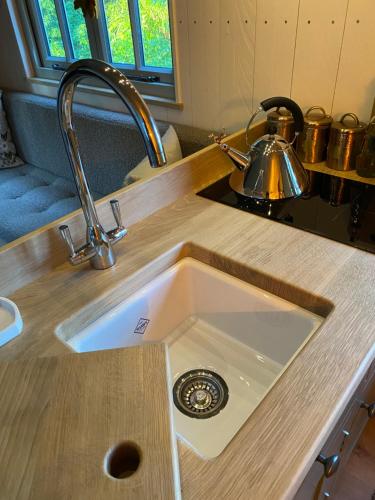 a kitchen sink in a counter with a tea kettle at Chez Maurice Luxury Shepherds Hut with Bath and Hot Tub in Kelling