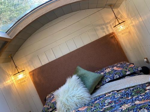 a bedroom with a bed with a wooden headboard at Chez Maurice Luxury Shepherds Hut with Bath and Hot Tub in Kelling
