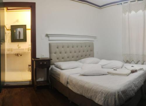 a bedroom with a bed and a bathroom with a shower at Pousada Solar do Carmo in Ouro Preto