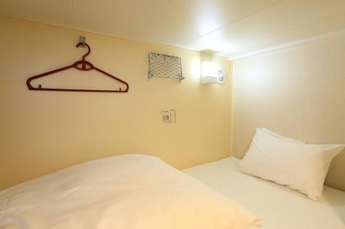 a small bedroom with a white bed and a hanger at Meimon Taiyo Ferry 1st sailing from Kitakyushu to Osaka in Kitakyushu