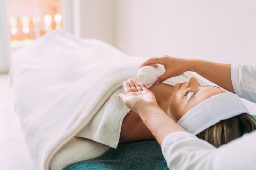 a woman laying in a bed with a towel at Naturhotel Reissenlehen in Bischofswiesen