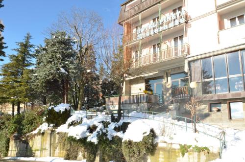 a building with snow on the ground next to a pond at Hotel Pineta in Loiano