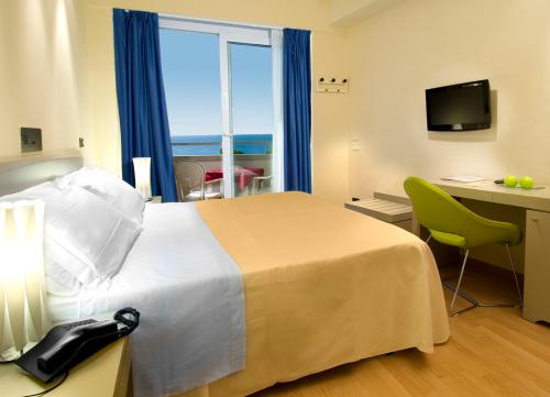 a hotel room with a bed and a desk and a window at Hotel Madison - Cattolica in Cattolica