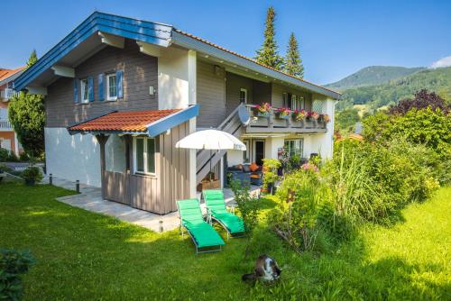 a house with chairs and an umbrella in the yard at Ferienwohnung Hörndlwand Ruhpolding in Ruhpolding