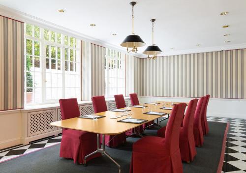 a conference room with a wooden table and red chairs at Brenners Park Hotel & Spa, Oetker Hotels in Baden-Baden
