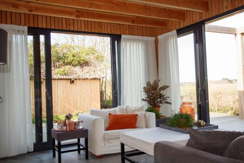 een woonkamer met een witte bank en glazen ramen bij Dunes of Egmond in Egmond-Binnen