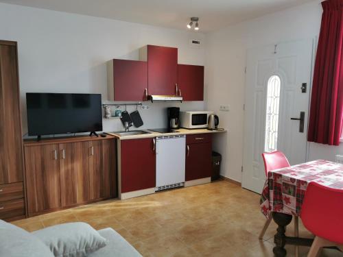 eine Küche mit roten Schränken und einem Tisch mit Tischtuch in der Unterkunft ​Gästehaus Frans-Jozef in Mönichkirchen