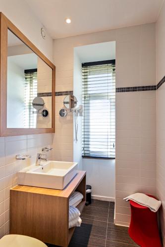 a bathroom with a sink and a mirror at Hotel Astoria in De Haan