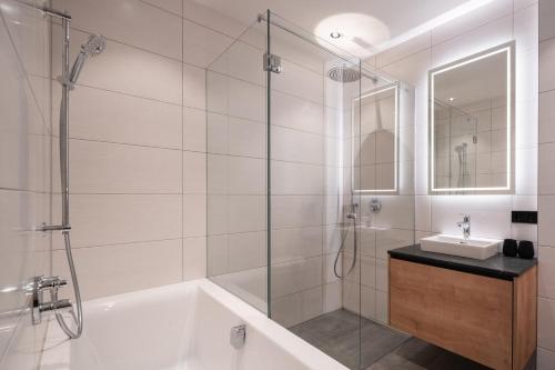 a bathroom with a shower and a tub and a sink at Das Chalet. in Mühlbach am Hochkönig