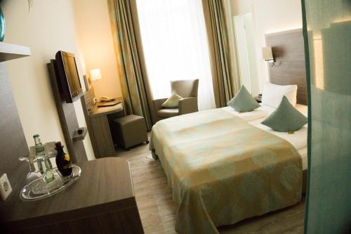 ein Hotelzimmer mit einem Bett und einem Stuhl in der Unterkunft Heerens Hotel in Emden