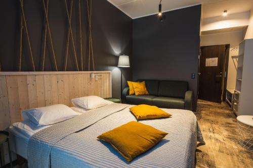 um quarto com uma cama com almofadas amarelas e um sofá em Tulivee Villa em Liimala