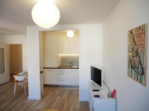 une cuisine avec des placards blancs et une table avec une télévision dans l'établissement Offre Spéciale - Appartement coup de cœur, à Nantes