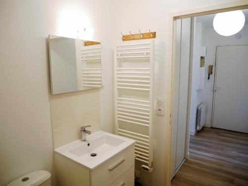 une salle de bain blanche avec un lavabo et un miroir dans l'établissement Offre Spéciale - Appartement coup de cœur, à Nantes