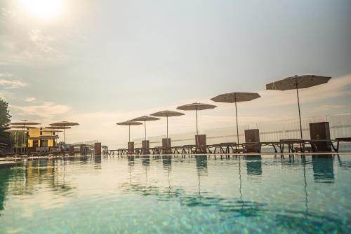 a swimming pool with tables and umbrellas at Atik Hotel in Unye