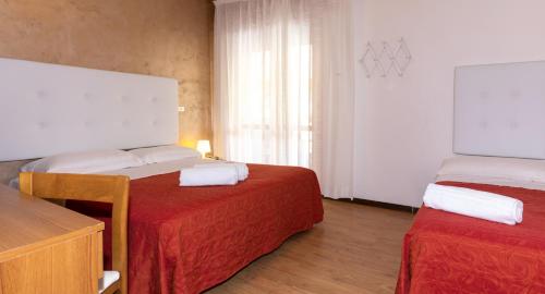 a hotel room with two beds and a dresser at Hotel Nazionale in Lido di Jesolo
