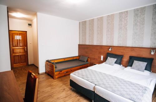 a bedroom with a bed and a bench in it at Lenti Thermal Panzió in Lenti