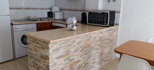 uma cozinha com um balcão com um micro-ondas e um lavatório em Alojamientos Rurales Aitana em Guadalest