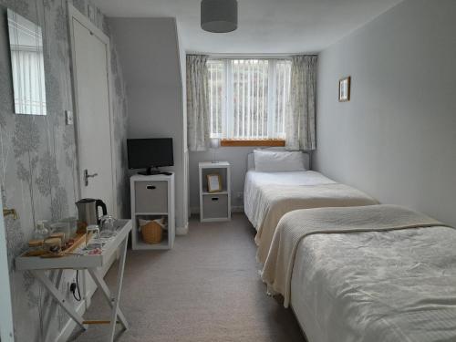 a bedroom with two beds and a desk and a television at Elderslie Guest House in Oban
