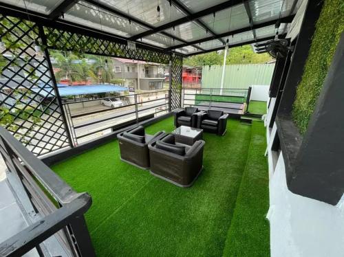 an outdoor patio with green grass and black furniture at The Sky Inn in Kuantan