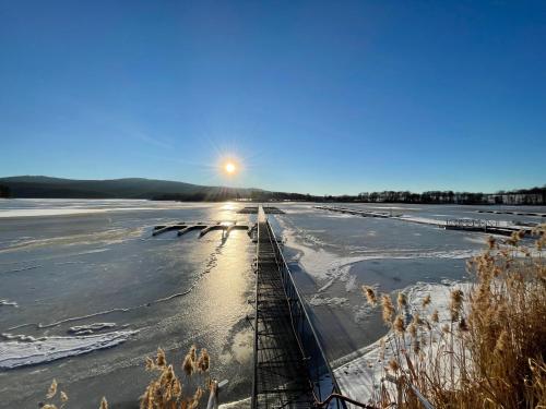a frozen lake with the sun setting on the horizon at Fontána Lipno in Černá v Pošumaví