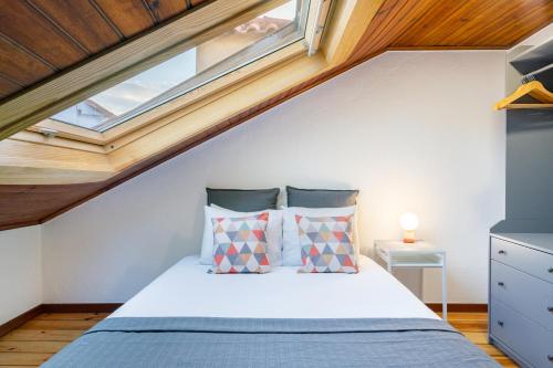 a attic bedroom with a bed with a window at WHome Beco Patacas Perfect location to explore Lisbon in Lisbon