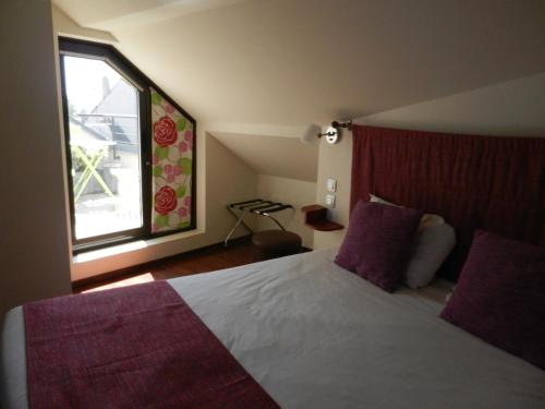 a bedroom with a bed with purple pillows and a window at L'HÔTEL de CHARTRES in Chartres