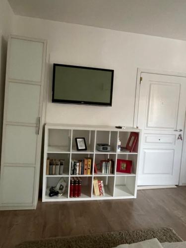 a white book shelf with a flat screen tv on a wall at Slavija Square Apartments in Belgrade