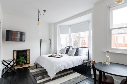 a white bedroom with a bed and a table at Doghouse Margate in Kent