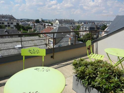 a balcony with chairs and tables and a view of a city at L'HÔTEL de CHARTRES in Chartres
